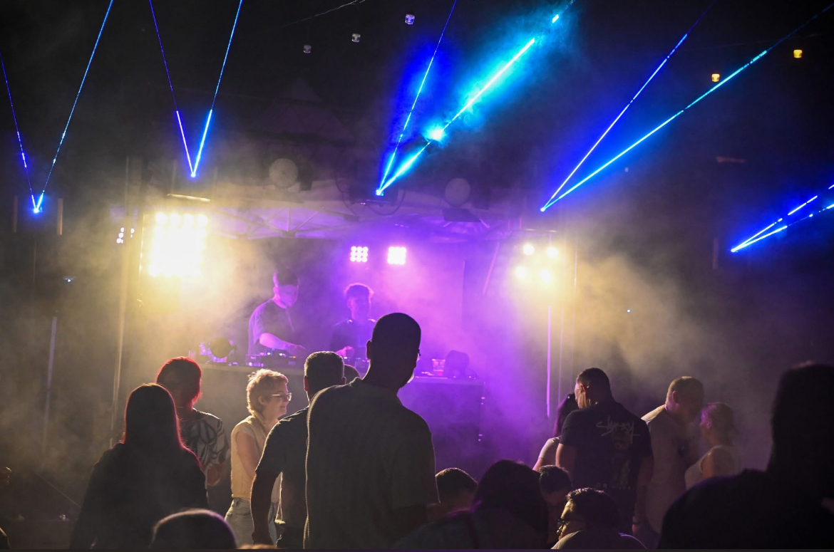 Outdoor stage lighting with warm wash, purple backlights, and blue lasers