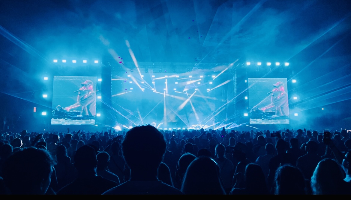 Concert festival crowd under sweeping blue sky laser beams